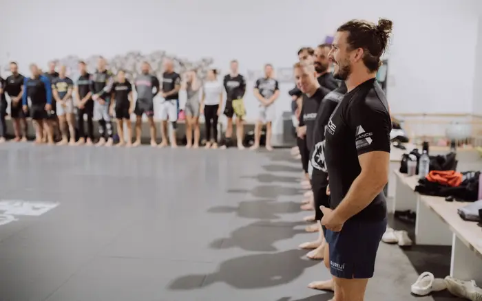 Head Coach Gino smiling as the Balance BJJ class lines up in rash guards before training
