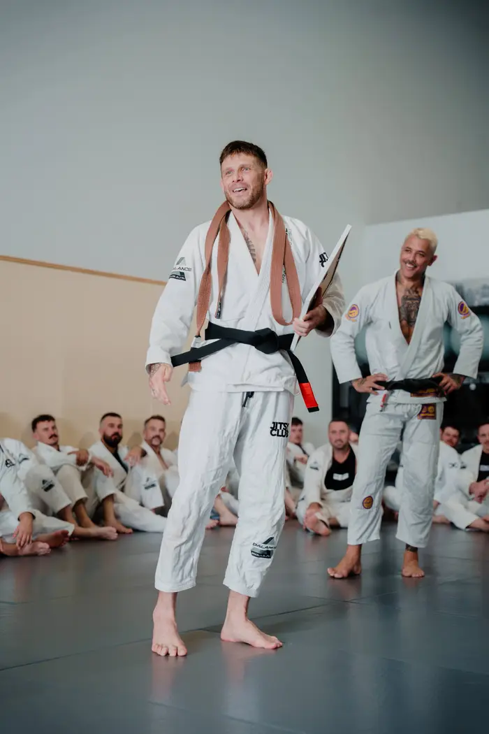 Balance BJJ coaches sharing a laugh on the mats during a belt grading