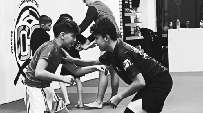 Two young students drilling stand-up grappling in the Close Quarters kids program