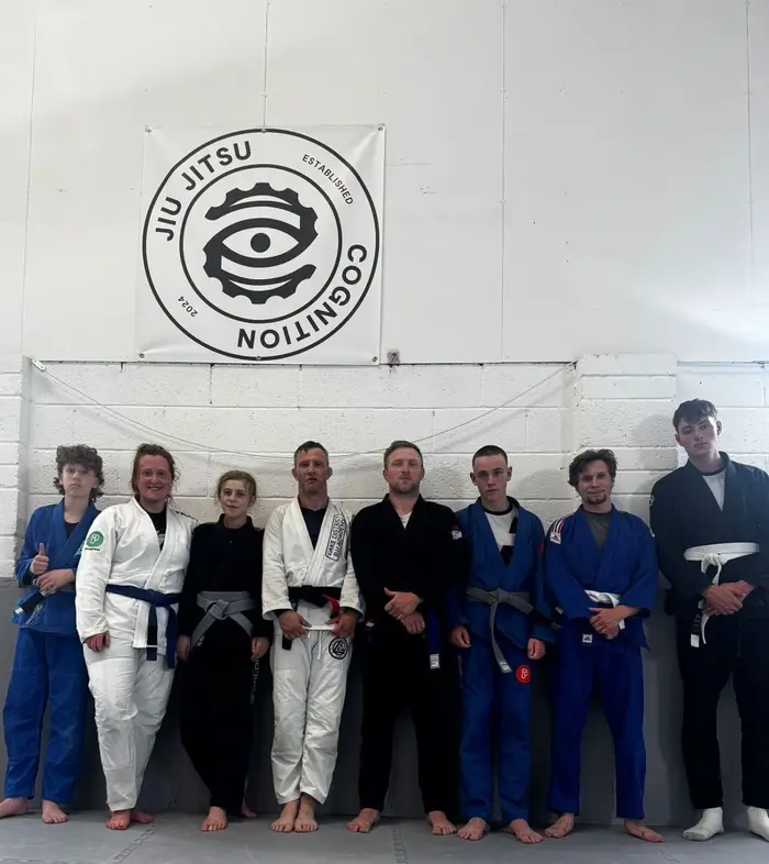 Cognition Jiu Jitsu gi class group photo under the academy banner