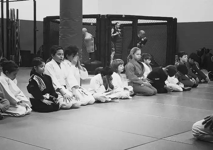 Kids martial arts class seated and focused on the mats