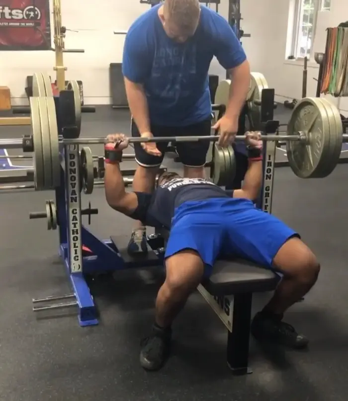 Lifter driving a loaded barbell off the chest on the bench press