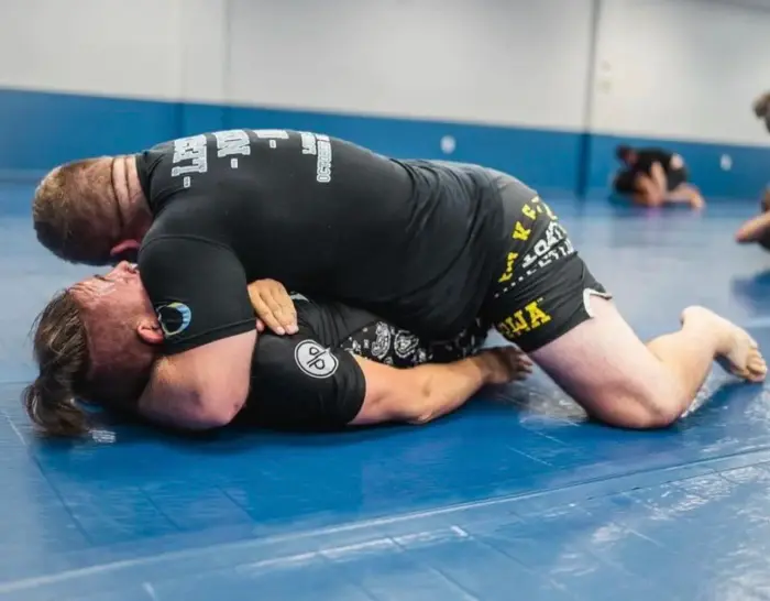 Two grapplers training jiu-jitsu on the mats