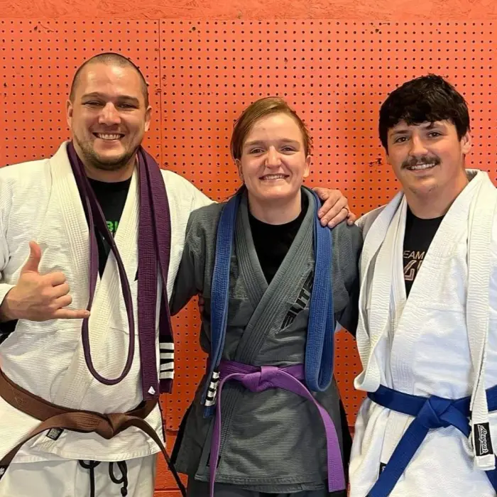 Three grapplers showing off their BJJ belts