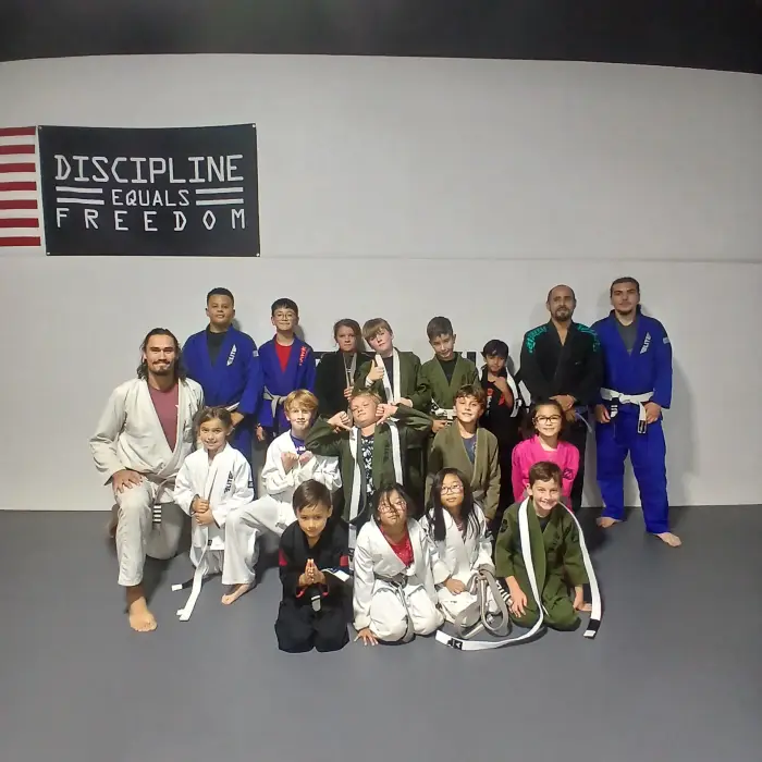 Revive Jiu Jitsu kids class team photo under the Discipline Equals Freedom banner