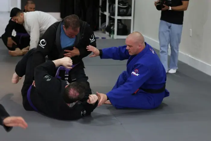 Professor Teddy in a blue gi working position with a training partner on the mats
