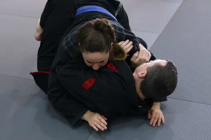 Professor Teddy coaching a student through a technique on the mat