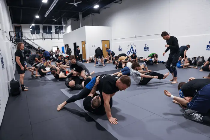 Students drilling positions during a class on the mats