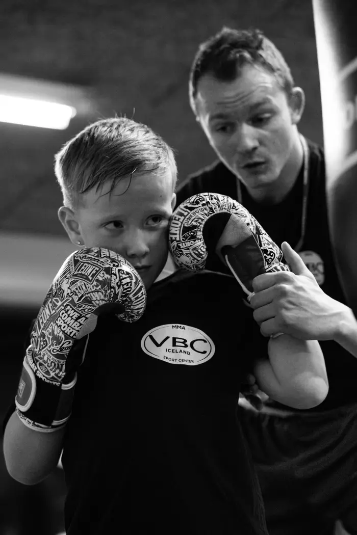 A young boxer working pads with a coach in VBC-branded gloves